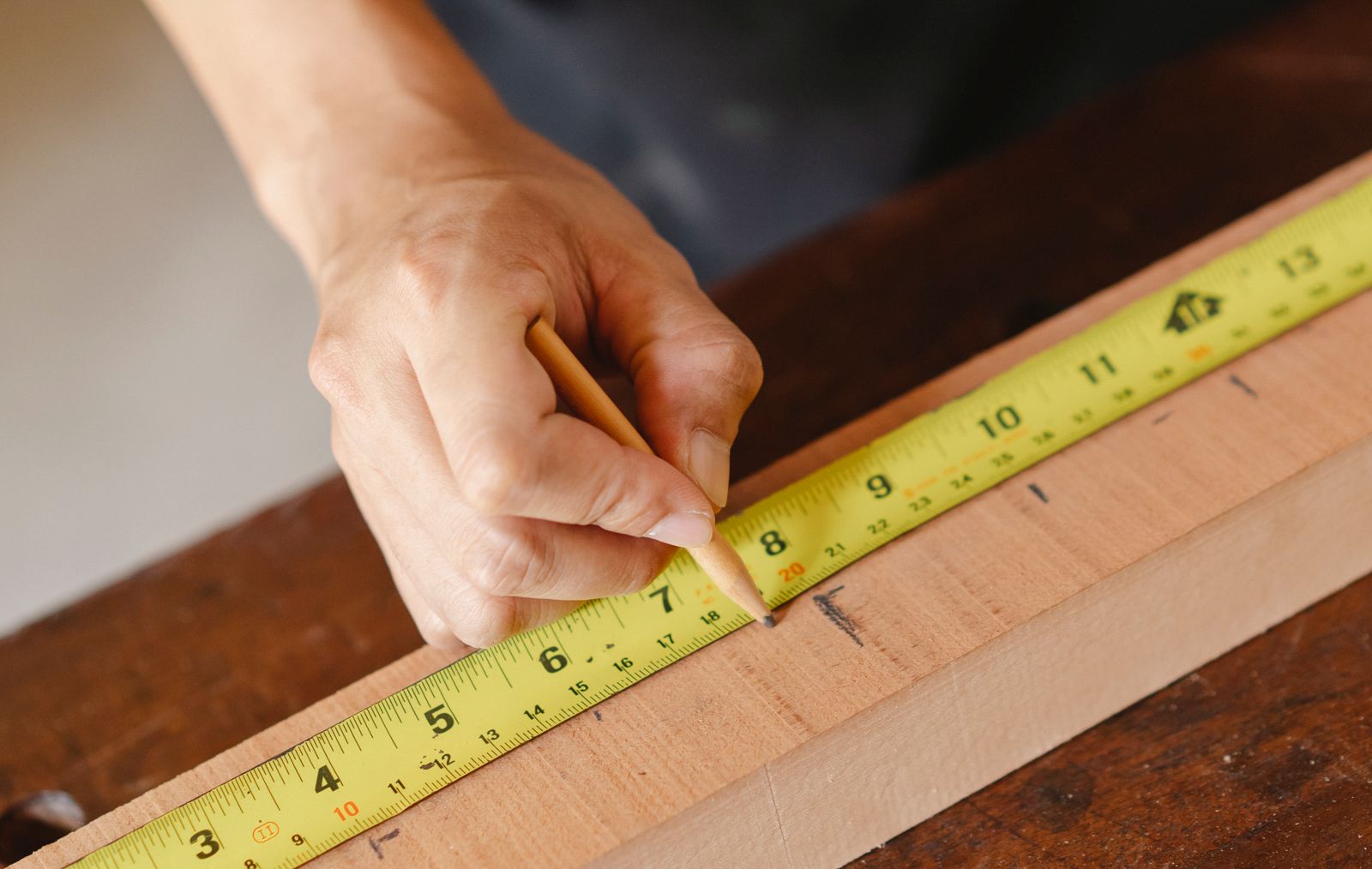 A carpenter measuring and marking timber on site