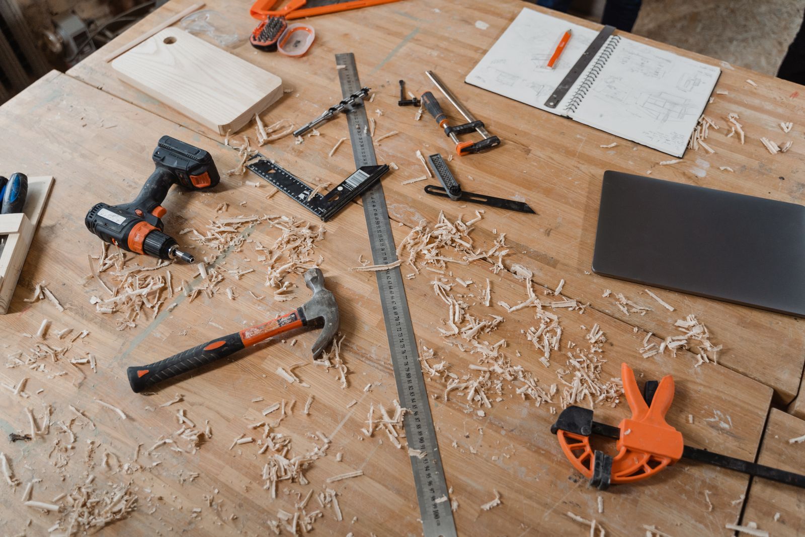 A workbench with shavings, a square, clamps and a sketchbook of drawings
